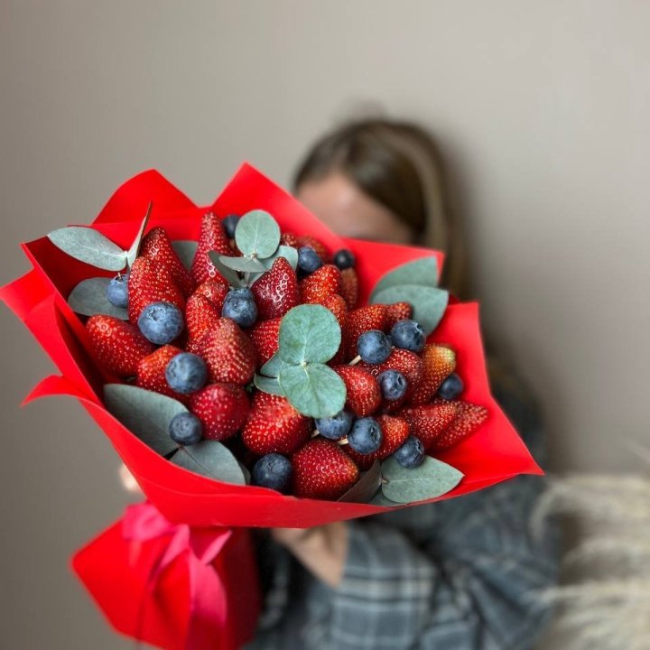 Florist placing large strawberries between flowers in an assembled bouquet